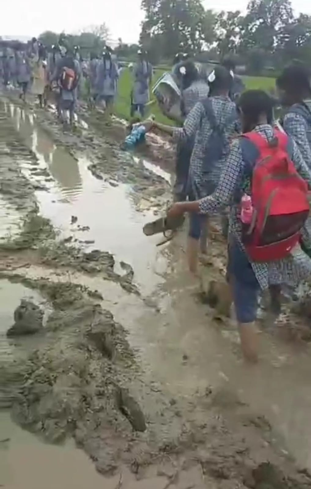 The future of the country walks in the mud with slippers in hands.